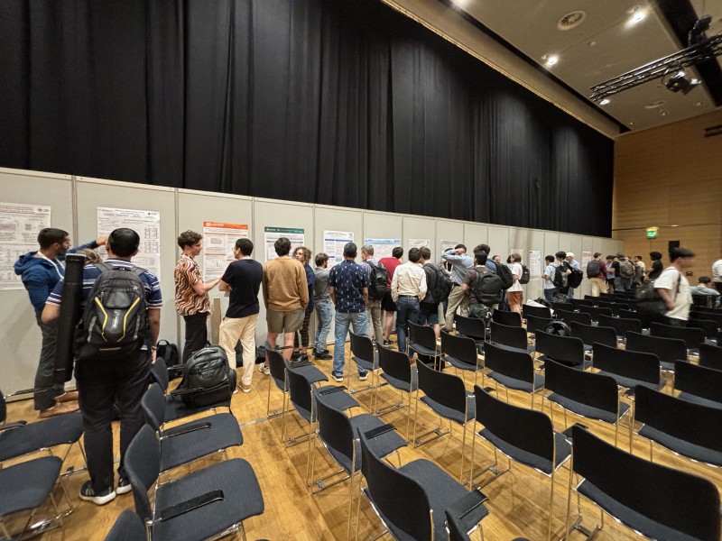 Small groups of researchers gathered in front of posters on the side of the workshop room