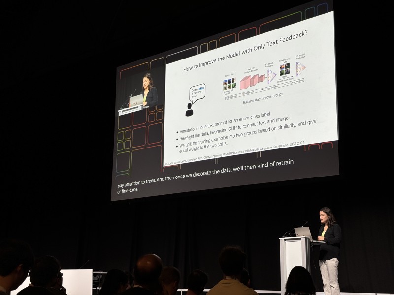 Chelsea Finn presenting a slide titled &lsquo;How to Improve the Model with Only Text Feedback&rsquo; on stage at ICML 2024