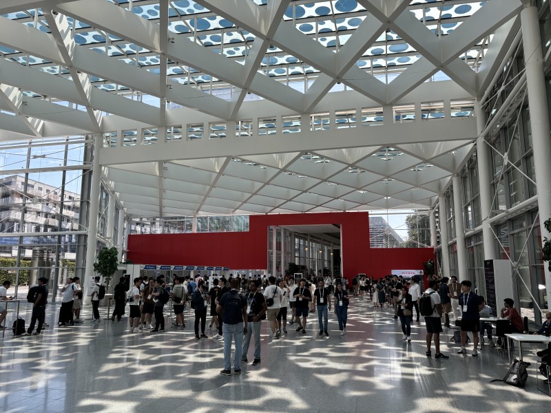 The entrance hall of hte conerence centre, with researchers standing around and the registration kiosks in the background