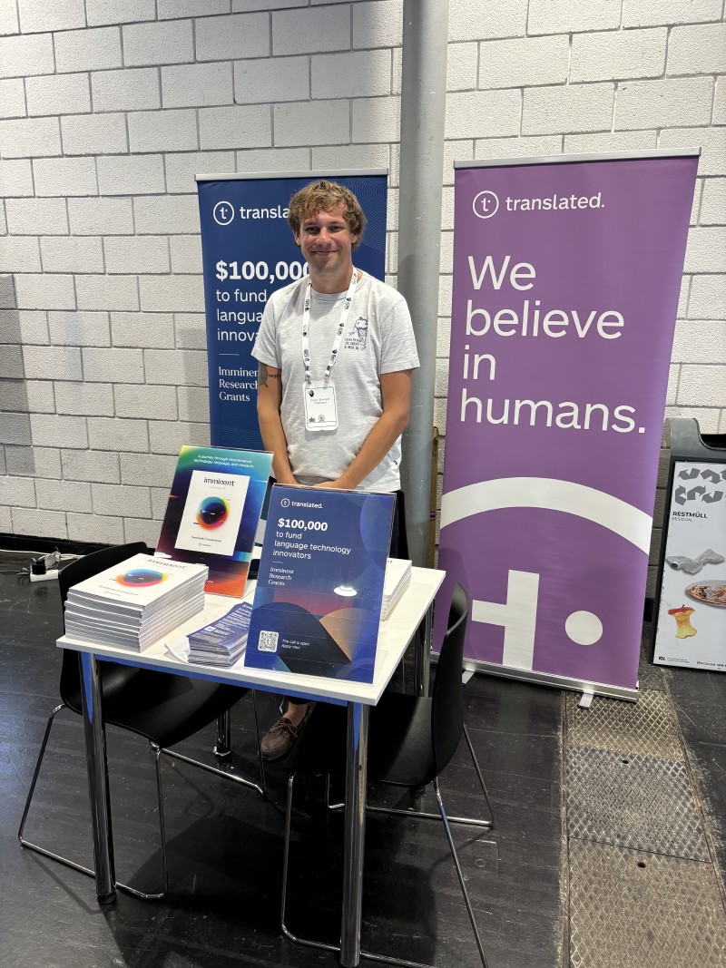 Translated’s exhibition hall stand, featuring a banner for their $100,000 in research grants