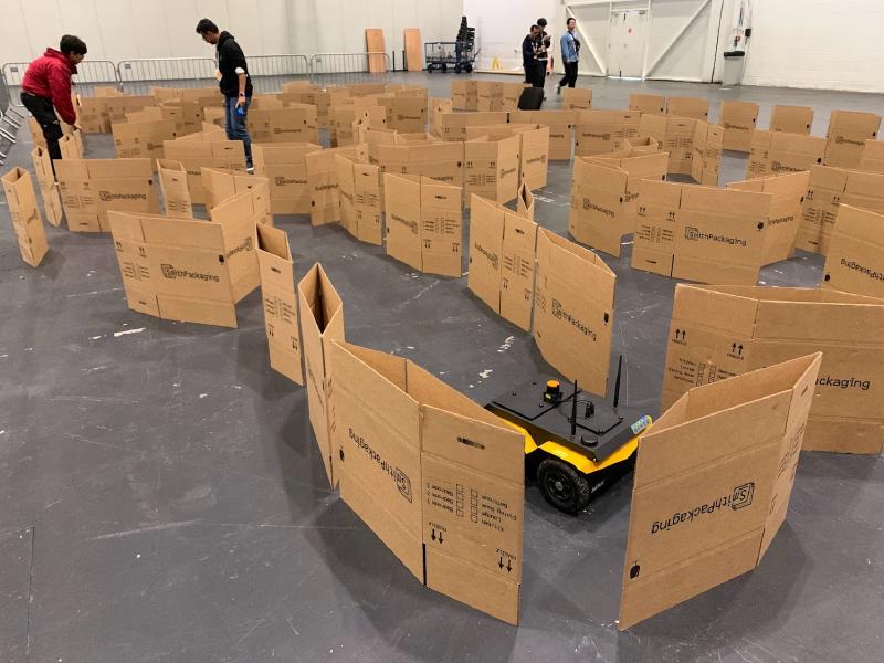 A Clearpath Jackal robot autonomously driving between walls of carboard boxes