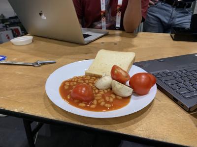 A plate containing untoasted bread, beans, sliced raw tomato and raw mushroom