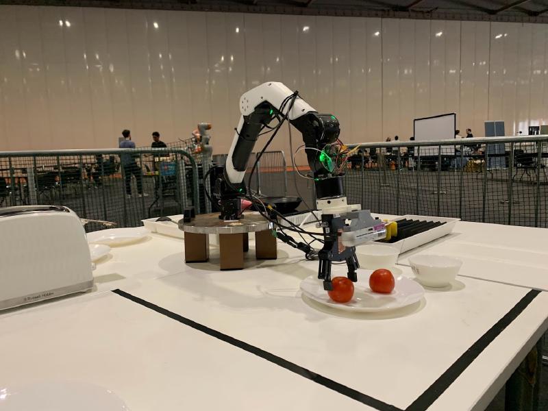 A robot arm picking up a tomato from a plate