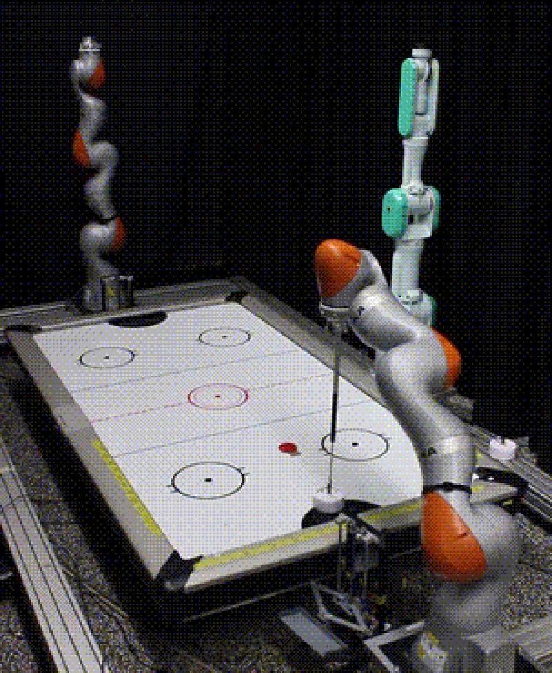 A robotic arm hitting an air hockey puck